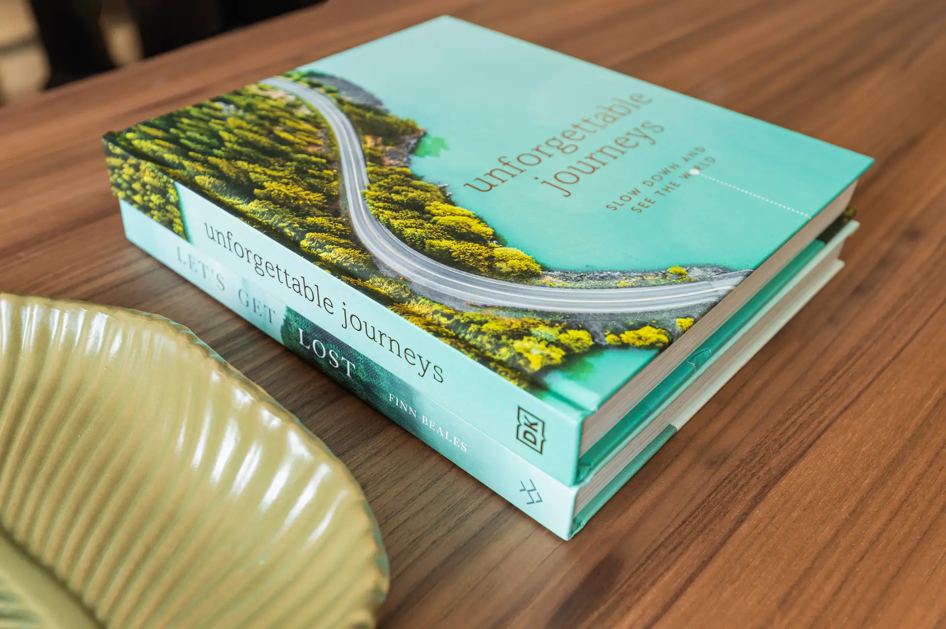Stacked travel books including 'Unforgettable Journeys' beside a leaf-shaped ceramic dish on a walnut table in an EirStay Dublin serviced apartment