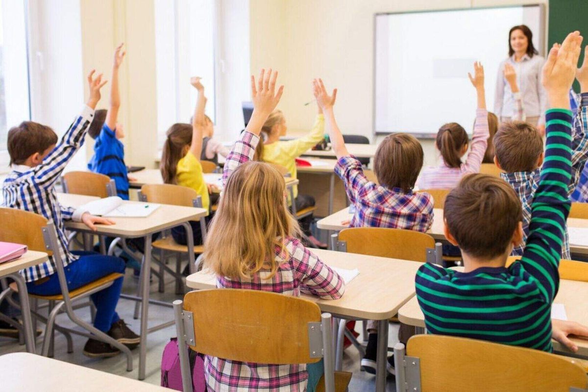 Children raising their hands in a Dublin primary school classroom — school places and waiting lists are a key consideration for families relocating to Dublin