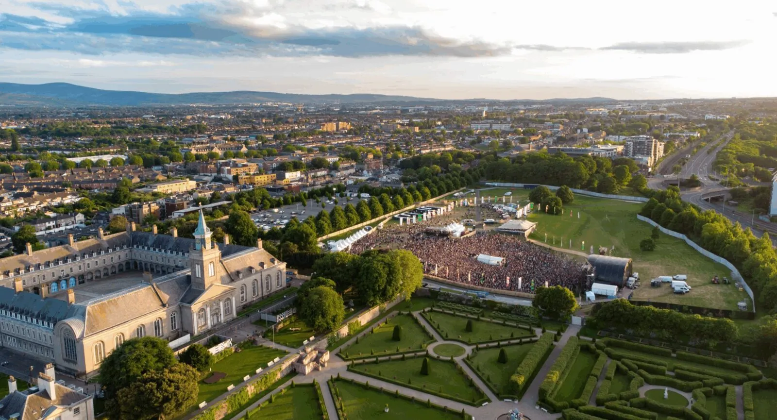 Aerial view of IMMA — the Irish Museum of Modern Art at the Royal Hospital Kilmainham, Dublin 8 — with Forbidden Fruit festival crowd filling the grounds and formal parterre gardens in the foreground, walkable from EirStay serviced accommodation in Kilmainham and Sandford Gardens