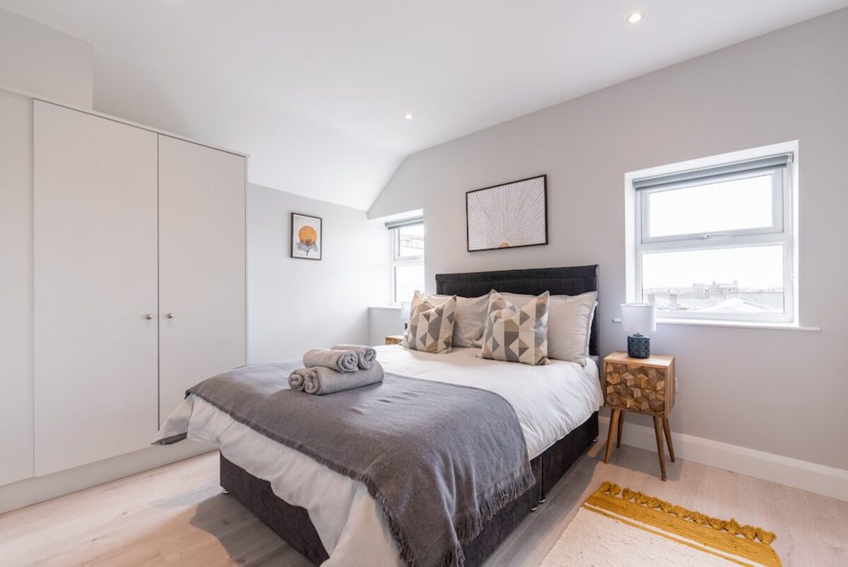 Spacious bedroom with fitted wardrobe wooden side table and yellow tassel rug in EirStay corporate accommodation Camden Street Dublin 2