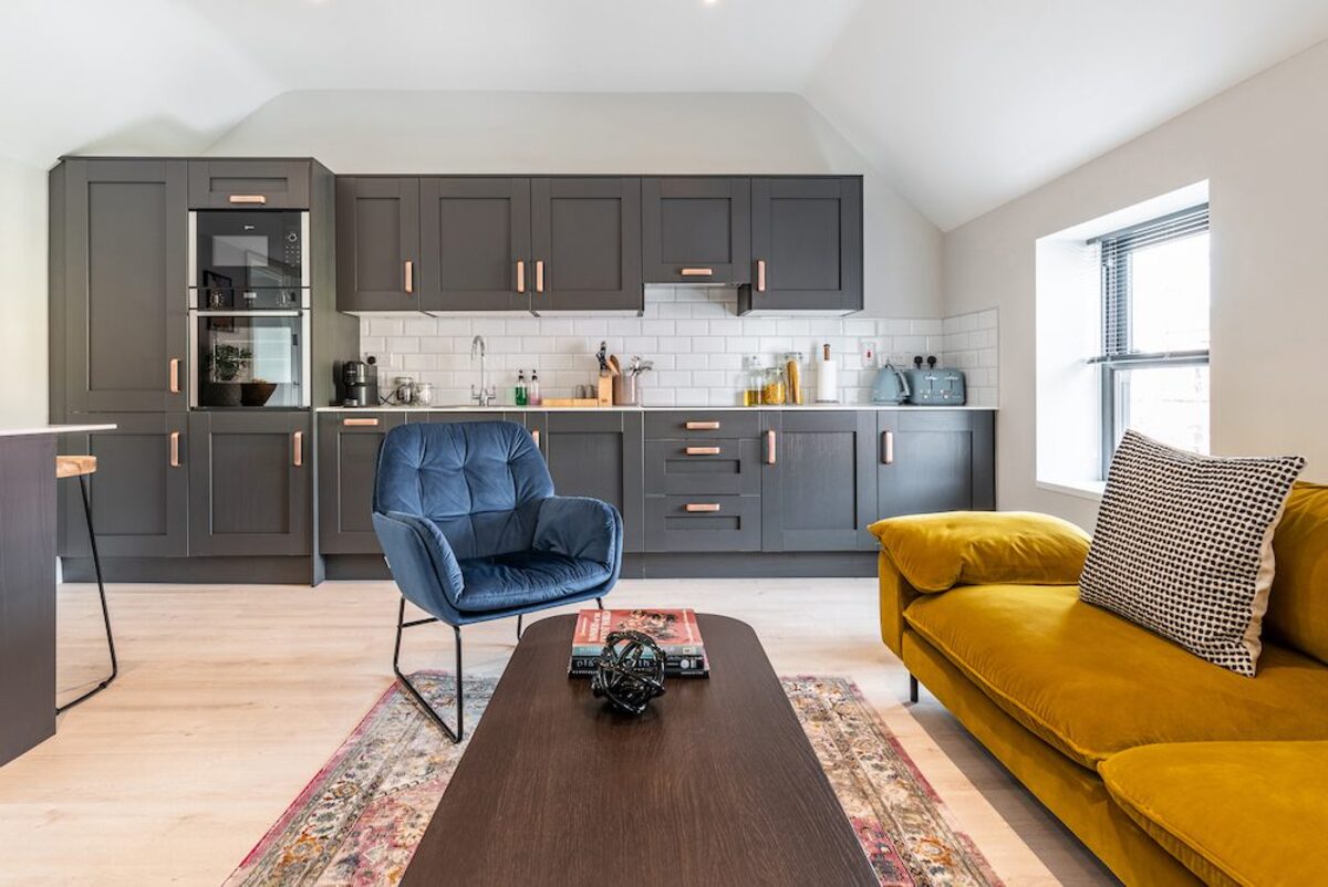 Full kitchen wall with shaker cabinetry and blue velvet chair in EirStay corporate accommodation Camden Street Dublin 2