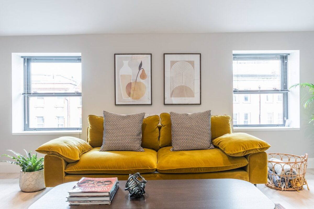 Mustard velvet sofa with geometric cushions and framed art prints in EirStay corporate accommodation Camden Street Dublin 2