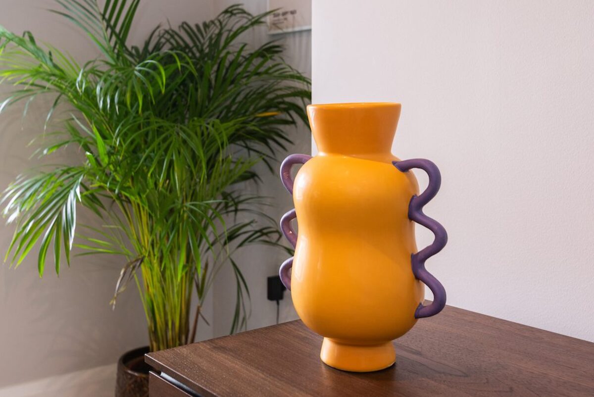Decorative yellow ceramic vase with purple handles and palm plant in EirStay serviced apartment Camden Street Dublin 2