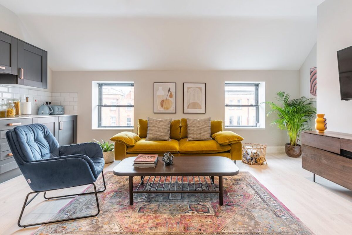 Living room with mustard sofa smart TV and walnut sideboard in EirStay serviced apartment Camden Street Dublin 2