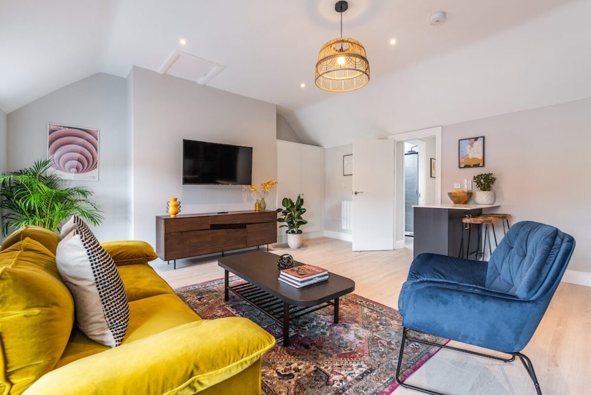 Living area with wall-mounted TV colourful prints and hallway in EirStay serviced apartment Camden Street Dublin 2