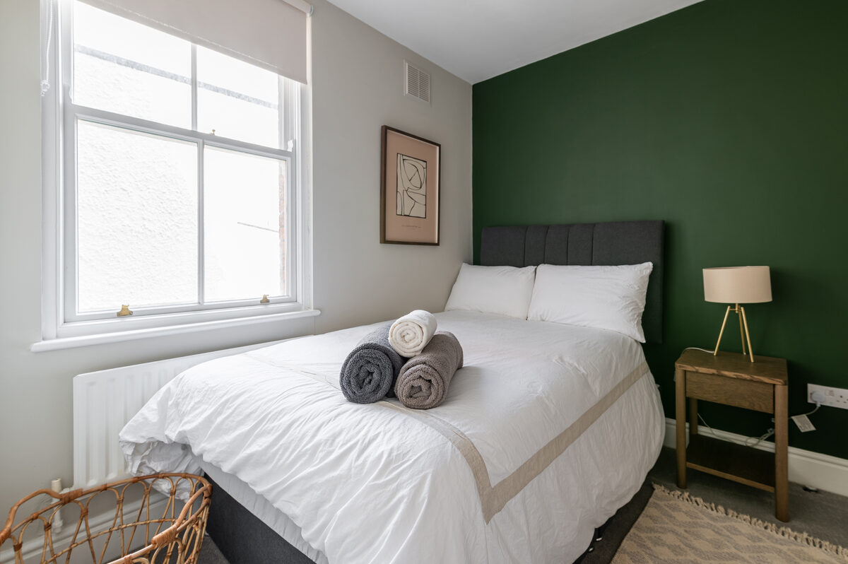 Double bedroom with green feature wall and fresh towels in EirStay short stay corporate serviced apartment Donnybrook Dublin 4