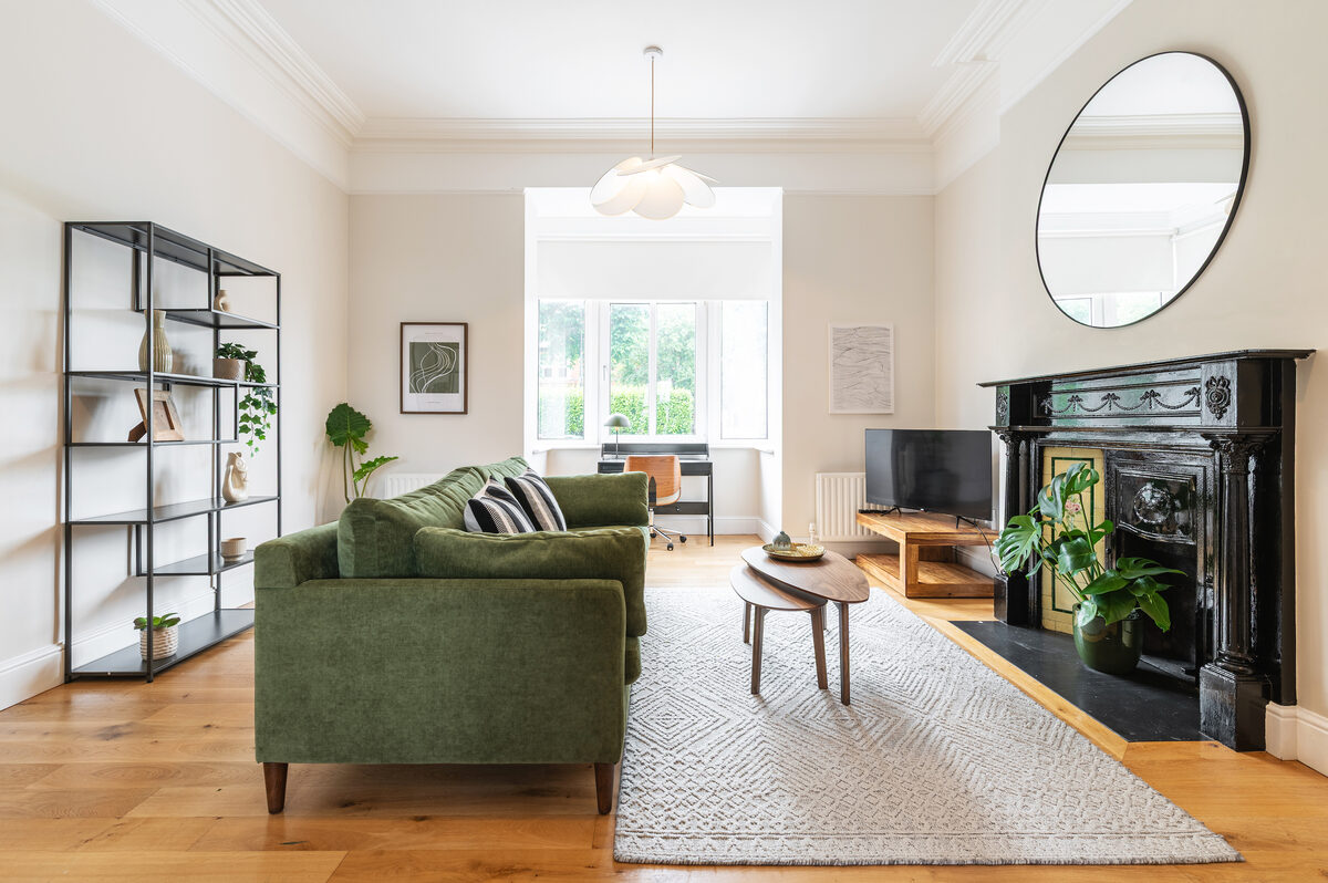 Stylish living room with green sofa and period fireplace in EirStay corporate short stay apartment Donnybrook Dublin 4