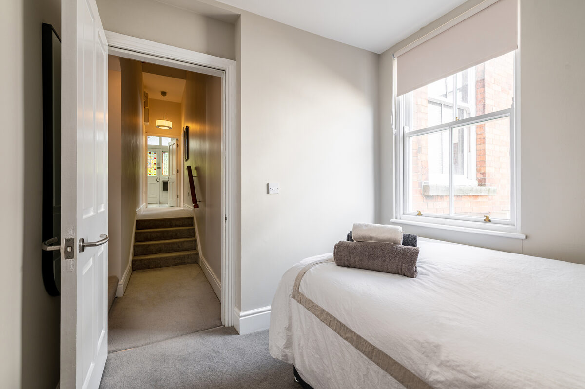 Single bedroom with fresh towels and stained glass hallway in EirStay short stay corporate apartment Donnybrook