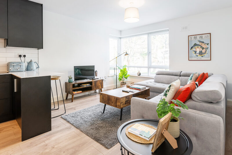Open-plan living and kitchen area in EirStay Islandbridge serviced apartment Dublin 8 — black fitted kitchen with breakfast bar and bright lounge