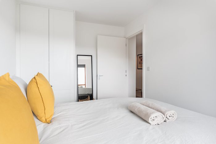 Bedroom with fitted wardrobe full-length mirror and fresh rolled towels in EirStay serviced apartment Kilmainham Dublin 8