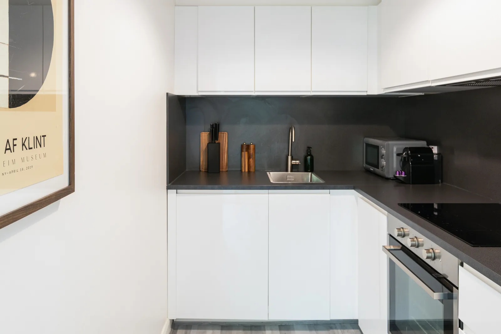 Rathgar apartment kitchen with white cabinets, oven, microwave and coffee machine