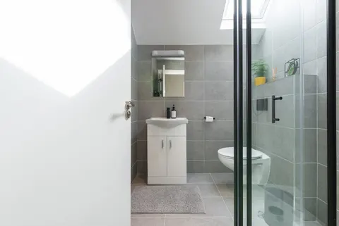 Modern bathroom with grey tiles skylight vanity and walk-in shower in EirStay corporate short stay apartment Camden Street Dublin 2