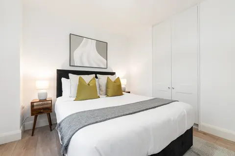Double bedroom with upholstered headboard, bedside lamps and fitted wardrobe in EirStay Islandbridge one-bedroom serviced apartment Dublin 8