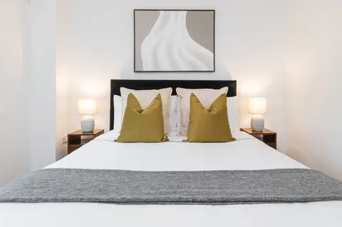 Double bedroom with grey throw, twin bedside lamps and framed art in EirStay Islandbridge one-bedroom serviced apartment Dublin 8