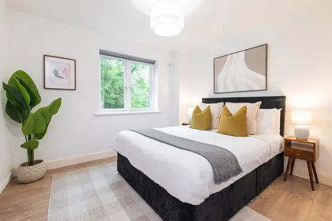 Double bedroom with bright window, house plant and bedside tables in EirStay Islandbridge corporate apartment Dublin 8
