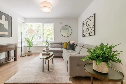 Spacious lounge with corner sofa, nest of tables and floor-height windows with tree views in EirStay Islandbridge corporate apartment Dublin 8