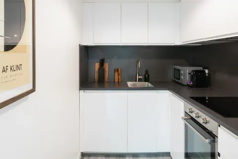 Rathgar apartment kitchen with white cabinets, oven, microwave and coffee machine