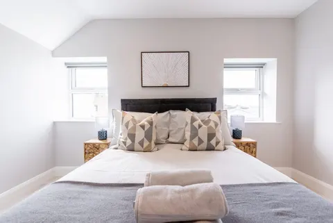 King-size bed with geometric cushions sunburst wall art and fresh towels in EirStay serviced apartment Camden Street Dublin 2