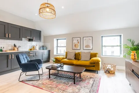 Spacious open plan living area with rattan pendant light and persian rug in EirStay serviced apartment Camden Street Dublin 2