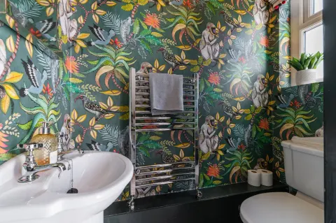 Bathroom with colourful botanical wallpaper, basin and heated towel rail at Sandford Gardens