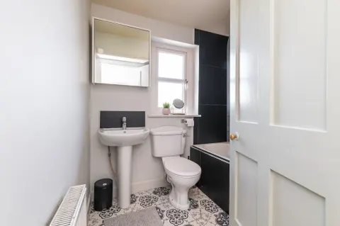 Main bathroom with a basin, bath and patterned floor tiles at Sandford Gardens
